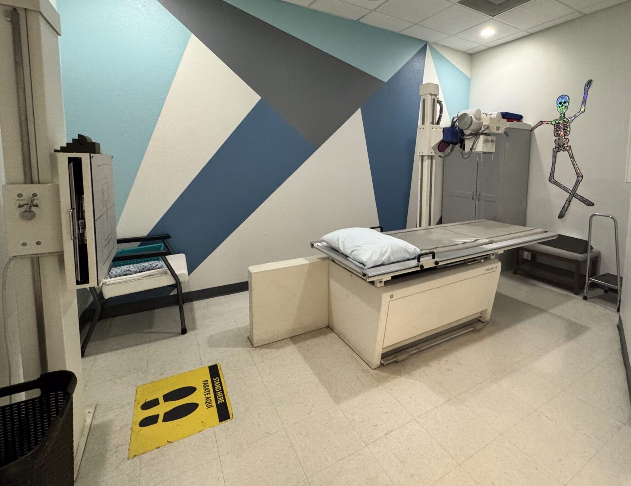 A clean, modern medical examination room with geometric wall art.
